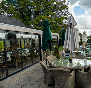 Image shows the conservatory and al fresco dining areas at The Duncombe Arms pub, in Ellastone, Staffordshire